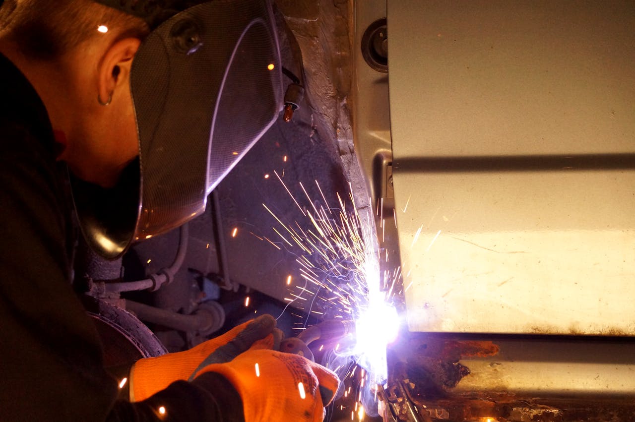 A focused welder working indoors, sparks flying from the welding torch.